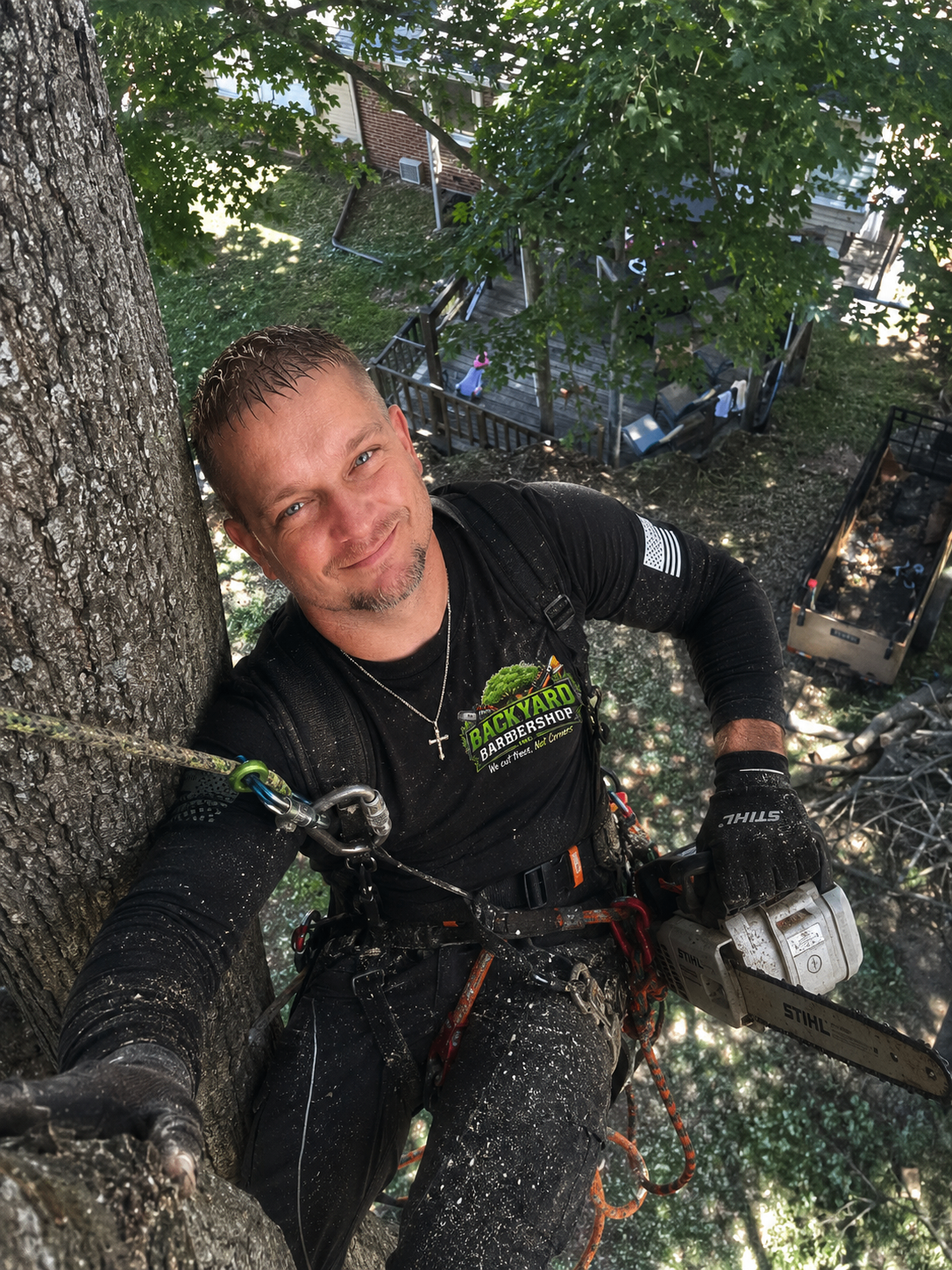 Christopher Wilson, co-owner of Backyard Barbershop Inc., climbing a tree with a STIHL chainsaw